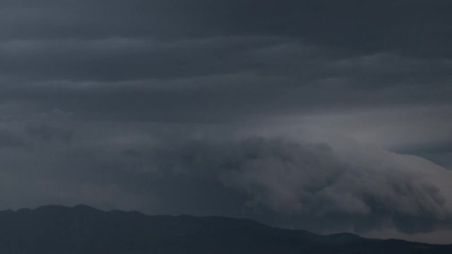 Spectacular clouds slithering over mountain range time-lapse