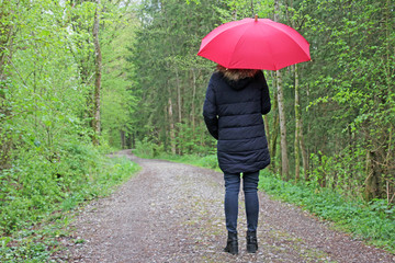 frau mit rotem regenschirm im wald 