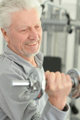 Elderly man in a gym with dumbbells