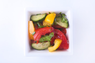 fresh vegetable salad with tomato, cucumber, bell pepper and lettuce leaf in white bowl.