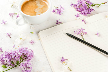 Obraz na płótnie Canvas Still life. Spring romantic mood. Breakfast. A cup of coffee, lilac and cherry flowers, a notepad for plans for the day, a pencil. On a white table. Copy space