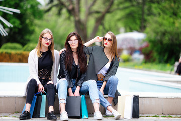 Three girls with shopping bags on park
