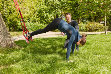 Frau bei Schlingentraining mit Personal Trainer