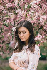  Portrait of a beautiful woman standing near a pink flowering apple tree