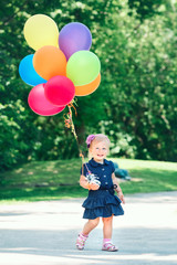 Portrait of cute adorable little Caucasian girl child in blue dress with colorful balloons, in field meadow park outside, happy birthday holiday celebration, lifestyle childhood