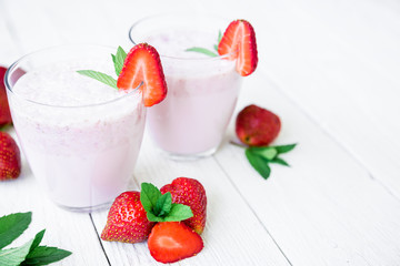 Smoothie with strawberry and flowers on white wooden background. Flat lay. Top view. Fresh milkshake