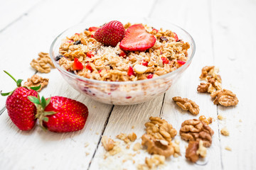 Oatmeal porridge with blueberries, strawberries, nuts and muesli on white wood background. Flat lay. Top view.