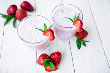 Strawberry smoothie with strawberry on white wood background. Flat lay. Top view. Fresh milkshake