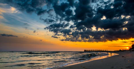 Gordijnen Old pier on background of sunset on beach © alexytrener