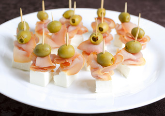 Meat canape with cheese on a white plate