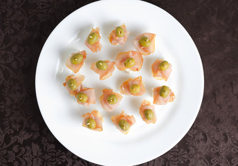 Meat canape with cheese on a white plate