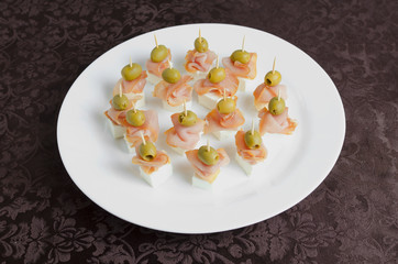 Meat canape with cheese on a white plate