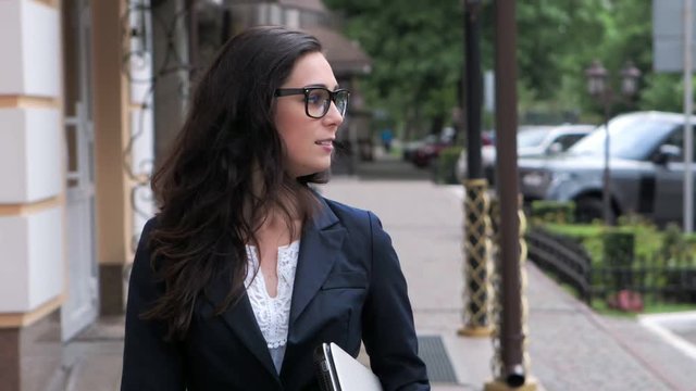 Close-up of attractive young businesswoman walking on urban street slow motion