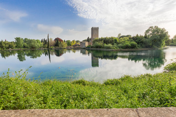 Fototapeta na wymiar View of the historical castle and spectacular lake of the Garden of Ninfa in the province of Latina, Italy, Europe