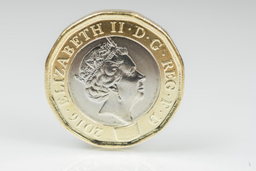 New British one pound sterling coin up close macro studio shot against a shiny reflective White...