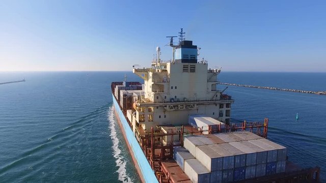 Aerial view of container ship passes through the channel goes into the open ocean after loading in the port of China at full speed. 4K.