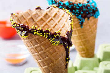Preparing chocolate dipped ice cream cones with candy  sprinkles