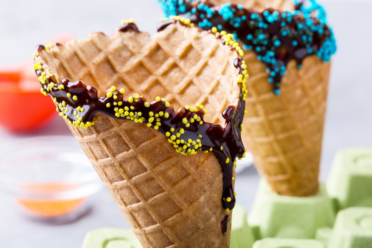Preparing chocolate dipped ice cream cones with candy  sprinkles