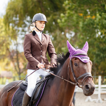 Young rider girl on horse at dressage competition. Equestrian sport background