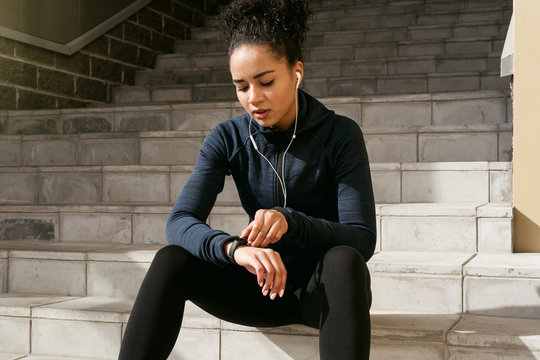 Young female runner checking her pulse with an activity tracker after training