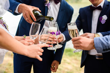 young man pours champagne in glass goblets. Young people in party rest after a hard day