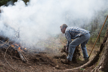 Man doing spring yard work around burn pile.