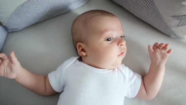 Newborn boy lies in a round bed on his back
