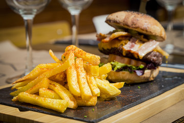 Traditional plate of chips and burger with glass on rustic table
