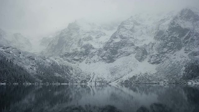 Frozen lake in winter mountain landscape with snowfall. Mointain in the winter weather.