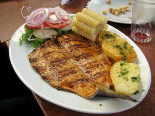 Peruvian dish - fried fish fillet with vegetables, onion, corn, boiled potatoes.