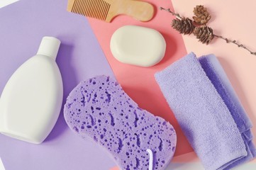 Flat lay bath products/ Shampoo, lilac washcloth, terry towel, wooden comb and soap