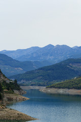 Mountains covered by pine forests descending to lake