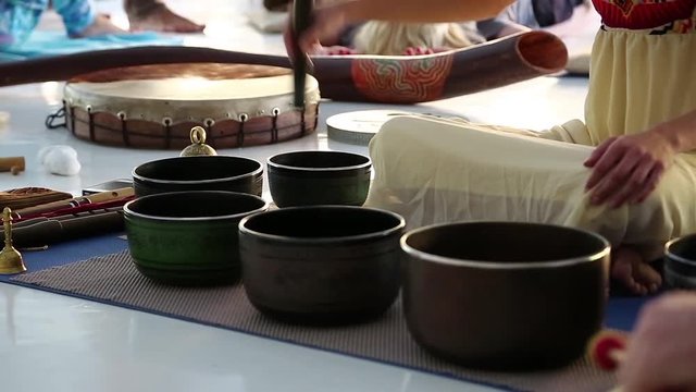 Woman operating with Tibetan singing bowls. Master-class with Tibetan singing bowls, musical group plays on Tibetan singing bowls
