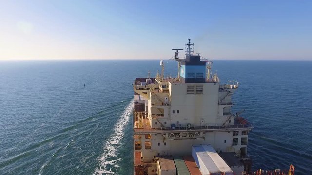 Aerial view of container ship passes through the channel goes into the open ocean after loading in the port of China at full speed. 4K.