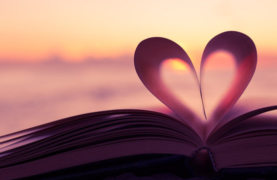 Heart shaped paper book against sunset. 
