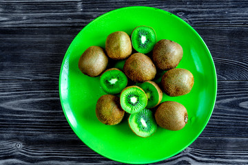 fresh green fruits with kiwi on plate on wooden background top view