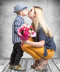 Small son gives his beloved mother a beautiful bouquet of pink roses and kisses mum ....