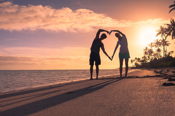 People and love concept. Young couple making a heart shape on the beach. 