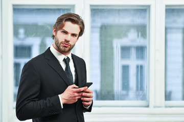 business, technology and people concept, serious businessman with smartphone