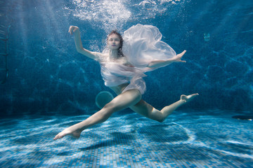 Woman dances underwater sports dance, her dress fluttering under the water.