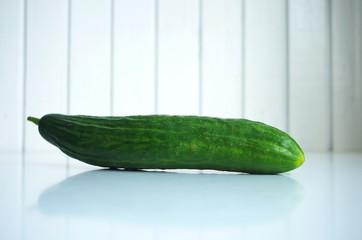 Fresh raw cucumber on kitchen table. With white wooden background.
