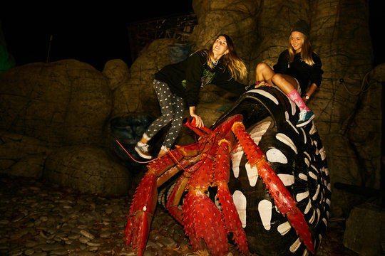 Girls fooling around a statute of crab in an entertainment park