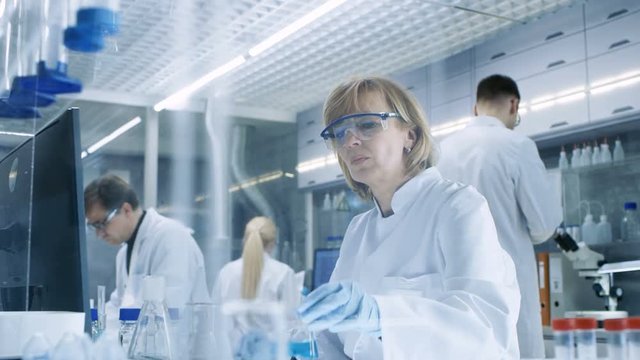  Shot on RED EPIC-W 8K Helium Cinema Camera.Female Scientist Analyzes Liquid in the Beaker and Types Down Observations on Her Computer. RED Cinema Camera UHD.