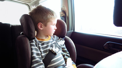 Little cute boy in a car seat looks out the window. Pure emotions over child face.