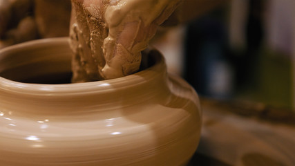 Potter is making clay pot bowl or vase ceramics porcelain on the potter's wheel. Creating pottery art and handicraft modelling creation.