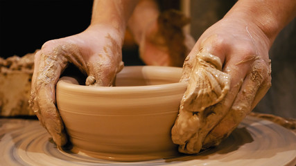 Potter is making clay pot bowl or vase ceramics porcelain on the potter's wheel. Creating pottery art and handicraft modelling creation.