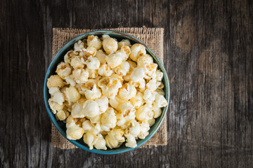 popcorn in a blue bowl top view on a dark wooden background