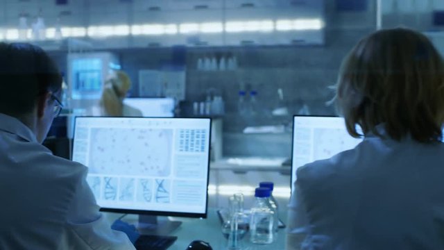 Moving Camera Shot of High Tech Ultra Modern Laboratory with Scientists Conducting experiments, Working on Computers, Looking at Substance under Microscope and Mixing Chemicals. RED Cinema Camera UHD
