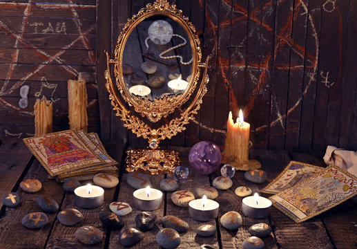 Magic ritual with ancient runes, mirror, tarrot cards and candles