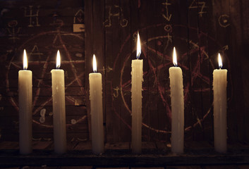 Mystic close up wih burning candles against wooden background with magic symbols